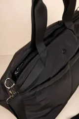 Bolso tipo shopper color beige, con asas fijas superiores y correa desmontable y regulable. Cuenta con dos bolsillos externos y tres bolsillos internos.