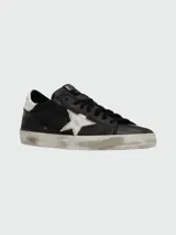 Zapatillas Golden Goose modelo Super-Star, color negro con estrella plateada y detalles en cuero blanco en el talón.