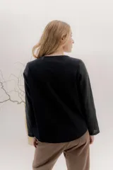 Remera de manga larga con escote a la base, color blanco, con un bordado central de dos líneas negras verticales en la parte delantera. La parte delantera es de lino y la espalda de algodón con spandex.