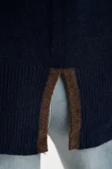 Sweater de tejido de punto con calce oversize, color azul marino con detalles en color marrón en las mangas y cuello. Presenta un diseño de manga larga y puños y ruedo acanalados.