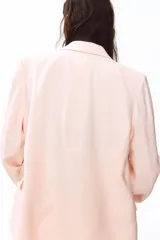 Blazer rosado de doble botonadura levemente largo con hombreras, solapas de muesca, bolsillos delanteros ribeteados con solapa y forro interior.