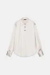 Camisa de manga larga confeccionada en tejido satinado con cuello solapa, cierre frontal con botones y bajo asimétrico.