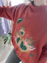 Buzo cropped de algodón color rojo con estampa frontal exclusiva de corazones con diseño de cerezas y hojas, manga larga y cintura elastizada.