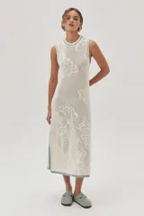 Vestido midi tejido de punto color crudo, con calados florales, calce recto, tajos laterales y detalles en celeste en cuello, sisas y ruedo.