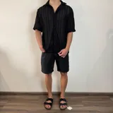 Camisa de manga corta confeccionada en tejido de crochet con diseño de rayas verticales, cuello solapa y cierre frontal con botones.