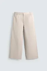 Pantalón de hombre de corte relajado, color beige claro, con cintura elástica, cierre frontal con botón y cremallera, bolsillos delanteros y bolsillos traseros de vivo.