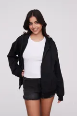 Campera canguro de algodón color negro, con capucha, cierre frontal completo y bolsillos delanteros tipo ojal. Diseño de mangas largas y calce holgado.