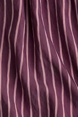 Short holgado de tela liviana color morado con finas rayas verticales blancas. Presenta cintura elástica fruncida con cordón ajustable y bajo redondeado con aberturas laterales.