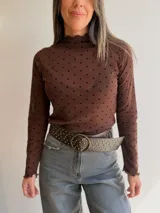 Remera de tul de manga larga con estampado de lunares negros sobre fondo blanco. Presenta cuello y bordes con terminación ondulada.