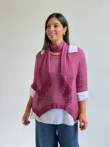 Sweater de punto color magenta con diseño asimétrico, cuello redondo y detalle de encaje bordado en el frente. Incluye una bufanda del mismo tejido y color, y se presenta superpuesto sobre una camisa blanca de algodón.