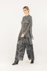 Camisa boxy oversize de viscosa y seda en color gris, con detalles de satén de viscosa y doble canesú en el frente y la espalda, teñida en frío. Tiene cuello mao, cierre frontal con botones, hombros caídos y mangas largas con puño, confeccionada en tejido liviano semitransparente.