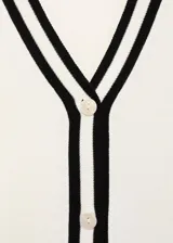 Cardigan de punto fino color blanco crudo, con diseño recto, escote en V, cierre frontal con botones y rayas negras en contraste en la tapeta y los puños.