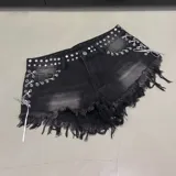 Short de denim negro con efecto lavado, tachas metálicas en la pretina, cordones cruzados con ojalillos y dobladillo desmechado con flecos.