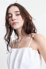 Top blanco con breteles finos, escote recto y corte peplum con frunces en la cintura.