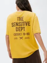 Camiseta de corte oversized color amarillo, con cuello redondo, mangas cortas y estampa pequeña en el pecho con el texto (DESDE) 18-80.