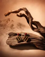 Aros colgantes artesanales con diseño geométrico romboidal, realizados mediante la técnica de taracea con láminas de madera en tonos naturales y negros, rematados con una esfera de coral rojo y engarce en plata.