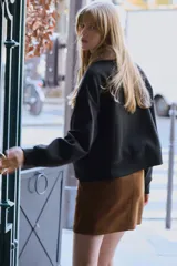 Buzo negro de felpa con interior suave, cuello de piel sintética en color marrón, mangas largas con hombros caídos y puños y bajo acanalados. Presenta tiras finas para atar en el frente.