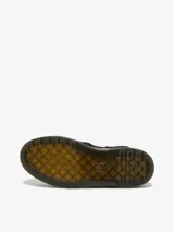 Zueco negro de gamuza con suela plana y correa ajustable en el talón.