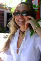 Collar con dije de forma irregular en tonos dorados y plateados, suspendido de un cordón doble de algodón negro.