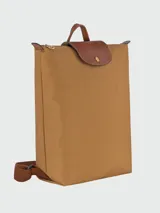 Mochila de diseño minimalista en color beige, con solapa y asa superior en cuero marrón texturizado. Cuenta con correas ajustables en color marrón y cierre principal.