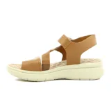 Sandalia de mujer color crema, con tira ancha sobre los dedos, tira cruzada sobre el empeine, pulsera con velcro al tobillo y plataforma baja.