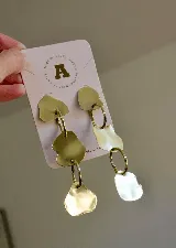 Aros colgantes dorados con tres piezas irregulares unidas por argollas. Hechos en bronce.