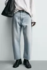 Jeans de hombre color azul claro con efecto lavado, de corte relajado desde la cadera que se estrecha ligeramente en el bajo. Tienen tiro medio, cinco bolsillos y cierre frontal con cremallera y botón.