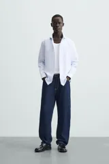 Camisa de algodón de manga larga, color celeste claro, con cuello italiano y cierre frontal de botonadura.