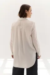 Camisa color crema de lyocell con cuello clásico, cierre frontal con botones, bolsillo de parche en el pecho y pespuntes a contraste en negro.