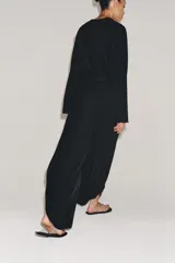 Pantalón de tiro medio confeccionado en hilatura de viscosa, de pierna ancha con pinzas en el delantero y bajo con abertura lateral. Cierre con cremallera oculta en costura.