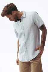 Camisa de lino de manga corta color celeste, corte regular y cierre frontal de botones.