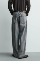 Jeans baggy fit de tiro medio, confeccionados en denim de algodón rígido con efecto lavado. Presentan un diseño de corte holgado y amplio en toda la pierna, con estilo clásico de cinco bolsillos y cierre frontal con cremallera y botón.