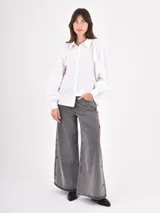 Camisa de manga larga en color celeste, con cuello clásico y cierre frontal de botones. Presenta un diseño con mangas abullonadas y puños ajustados.