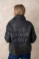 Campera puffer de acabado satinado en color beige, con cuello alto, cierre frontal y bolsillos laterales. Presenta un diseño moderno y sofisticado.