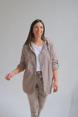 Campera tipo parka liviana color visón, con cierre frontal, capucha con cordones ajustables y mangas 3/4 con detalle de trabilla. Presenta un diseño holgado y casual.