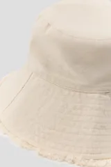 Gorro tipo bucket de algodón color beige, con ala ancha con acabado deshilachado y pespuntes, y cordón ajustable con stopper.