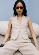 Pantalón de lino color beige, de corte recto y largo cropped, con cintura elástica, trabillas y cierre frontal con cremallera y botón.