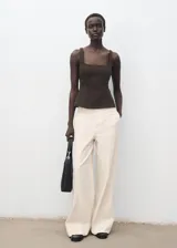 Pantalón de tiro alto estilo wide leg, color blanco, con trabillas para cinturón, bolsillos laterales y cierre oculto con botón, gancho y cremallera. Confeccionado en tejido de algodón.