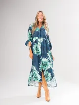 Vestido camisero largo con estampado floral en tonos rojos y negros, con cuello camisero, abotonadura frontal y mangas largas con puños abotonados.