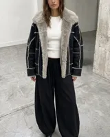 Campera tipo gamulán de cuero sintético negro con interior y solapas de piel sintética en color gris. Presenta costuras visibles y diseño de paneles.