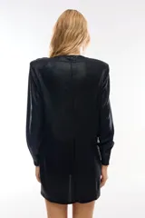 Minivestido negro con brillos, mangas largas y hombreras.