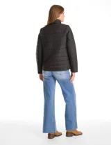 Campera 3 en 1 de color beige, con sistema de capas desmontables. La capa exterior es de tejido técnico resistente al viento y lluvia ligera, con capucha fija, cierre frontal con solapa, bolsillos de parche y ajuste elástico interno en la cintura. Incluye una campera interior capitoneada ultraliviana que puede usarse de forma independiente.