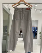 Jean de corte baggy en color gris, con diseño de costuras verticales y paneles en las piernas. Cuenta con cierre de botón metálico y bolsillos laterales.