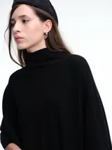 Poncho amplio de cuello alto, confeccionado en hilado con lana y cashmere, con diseño de caída recta y botones laterales.