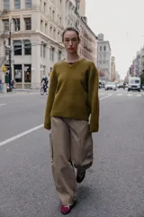 Jersey de punto negro, con cuello en V (pico) y manga larga, acabado en rib en puños, cuello y bajo.