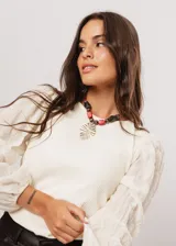 Blusa color manteca de cuello redondo y mangas largas abullonadas con puños elásticos.