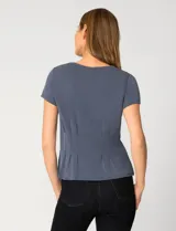 Remera blanca de manga corta con cuello redondo, confeccionada en una mezcla de modal, poliéster y elastano. Presenta un diseño con alforzas verticales en el frente que aportan estructura y una silueta relajada.
