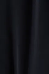 Top negro de manga larga con escote redondo y un nudo ajustable en el lateral inferior.