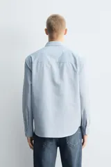 Camisa de corte relajado confeccionada en una mezcla de algodón, lyocell y seda de origen italiano. Presenta cuello abotonado, manga larga con puños abotonados y cierre frontal con botones.