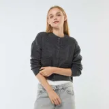 Chaqueta cropped de punto color gris oscuro, con cuello redondo, manga larga y cierre frontal con botones.